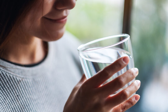 Closeup image of a beautiful young asian woman holding a glass of water to drink