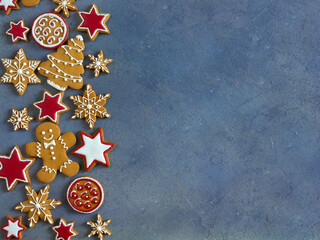 Christmas gingerbread cookies ornament on dark background with copy space. Glazed painted cookies: snowflakes, stars, gingerbread man, balls. Christmas and New Year decoration and greetings consept.
