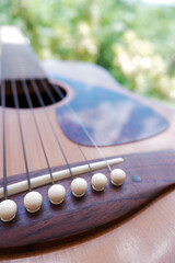 Closeup of acoustic guitar with nature background and reflection of clouds on pickguard