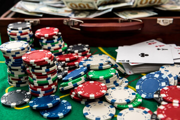 Naklejka premium Suitcase with dollars, playing card, poker chips on the green poker table
