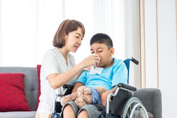 asian mother feeding drinking water to disabled child on wheelchair