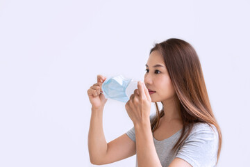 Beautiful young Asian woman holding protective face mask on white background. New normal, prevent pollution and disease concept