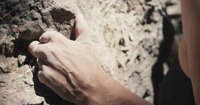 Female paralympic climber woman athlete missing fingers on left hand holds grip chalk on stone rock climb ascends outdoors lifestyle sport in nature unrecognizable macro close up slow motion