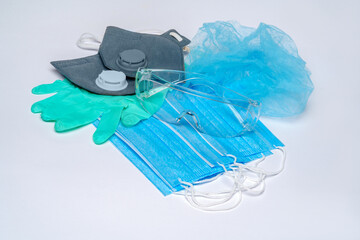 disposable medical face masks, pair of latex gloves. hat and protective glasses over light grey background