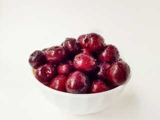 Bright juicy red cherry on a white background in drops of water.