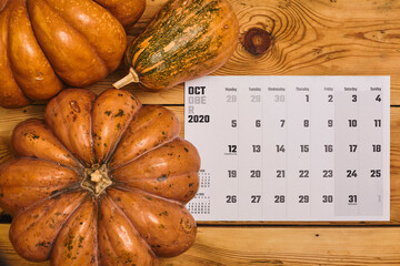 Simple 2020 October monthly calendar on the wooden desk with a pumpkin