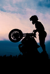 The silhouette of a motorcyclist at sunset. Moto rider making a stunt on his motorbike.