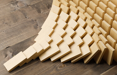 Wooden domino stones pyramid on wood floor falling over, chain reaction or multiplication effect concept