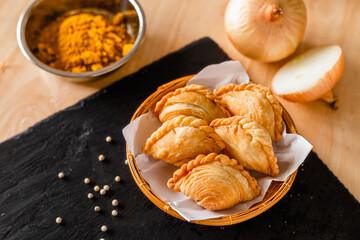 Curry puff on a dark plate and ingredients