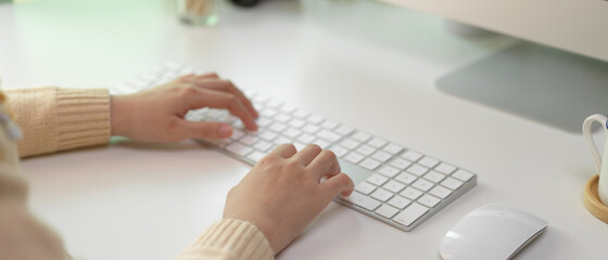 Female employee typing on computer keyboard on white office desk in office room