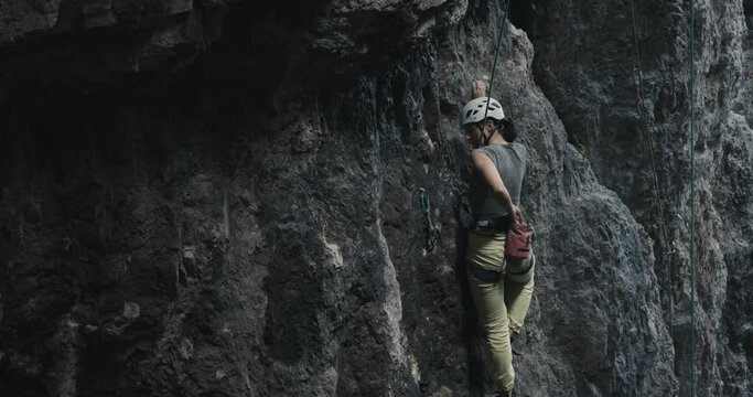 Female climber woman athlete wear helmet pause rock climb reach in chalk bag continue ascend outdoors lifestyle sport in nature