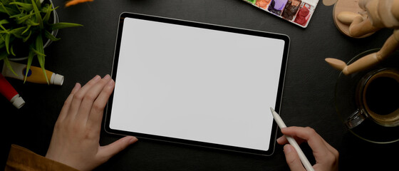 Female designer drawing on mock up tablet with stylus pen on worktable with painting tools © bongkarn