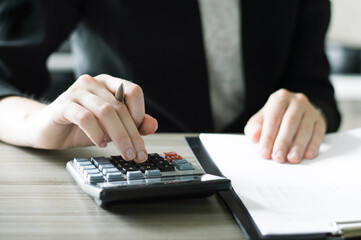 accountant working at a table using a calculator to calculate numbers, financial accounting concept. Finance