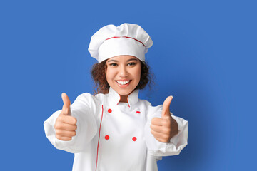 Female African-American chef showing thumb-up on color background