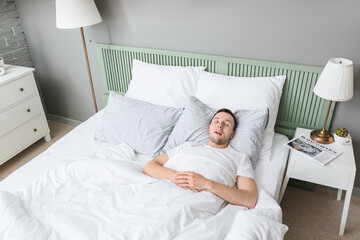 Young man snoring while sleeping in bed. Apnea problem