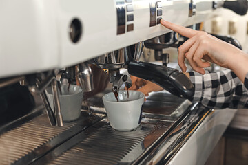 Young barista making coffee in cafe, closeup