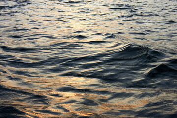 Closeup of water rippled surface with sunshine at sunset evening time at the river