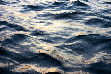 Closeup of water rippled surface with sunshine at sunset evening time at the river