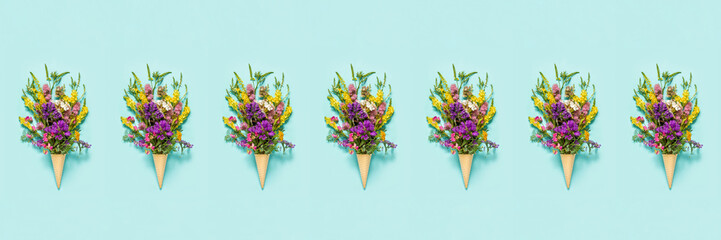 Flower pattern. Bouquet field colored flowers in waffle ice cream cone on blue paper background Creative Flat Lay Top view Banner