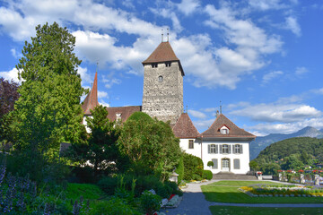 Fototapeta na wymiar A monument of architecture, the medieval castle in Spiez, Switzerland. Green garden for walking, summer Sunny weather, blue sky, green grass.