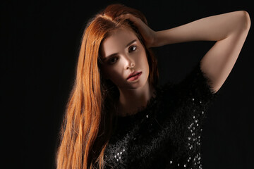 Beautiful young redhead woman on dark background