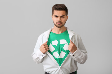 Man wearing t-shirt with recycling sign on grey background. Ecology concept