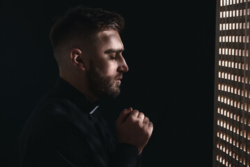 Young priest in confession booth