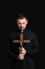 Fototapeta na wymiar Handsome priest with cross on dark background