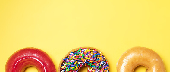 Top view of chocolate frosted donut with sprinkles, sugar-glazed frosted and strawberry glazed...