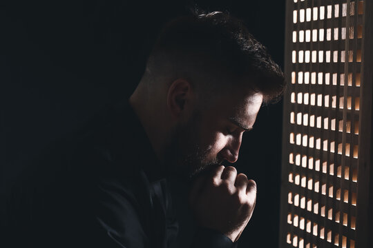 Young priest in confession booth