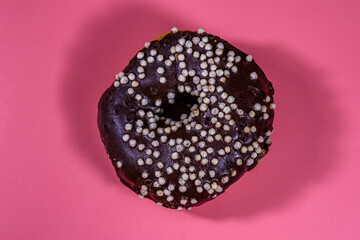 Donut with chocolate glaze on top isolated on a pink background
