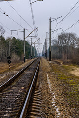 Fototapeta na wymiar Railroad track and electrical power line in the forest at autumn