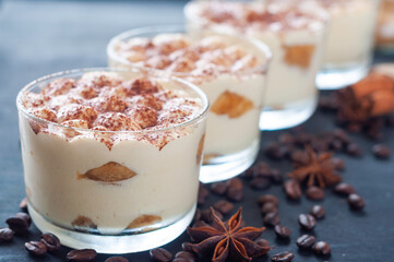 exquisite tiramisu in glasses decorated with cocoa powder on a dark background