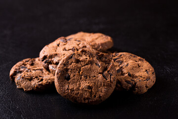 Appetizing chocolate chip cookies with slices of raisins on a black background.