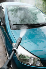 Obraz premium Car wash at home alone. Car wash high pressure close-up. A man washes a green car.