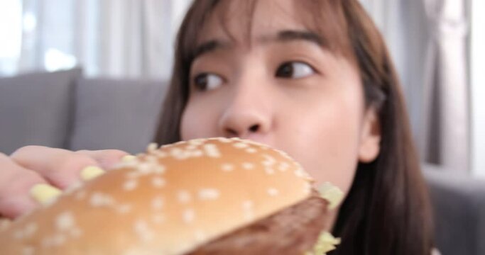 Close up asian woman takeaway eating junk food hamburger and pizza.