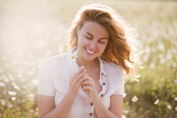 Young beautiful woman relaxing in chamomile field.