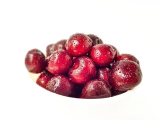 Bright juicy red cherry on a white background in drops of water.