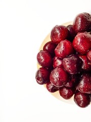 Bright juicy red cherry on a white background in drops of water.