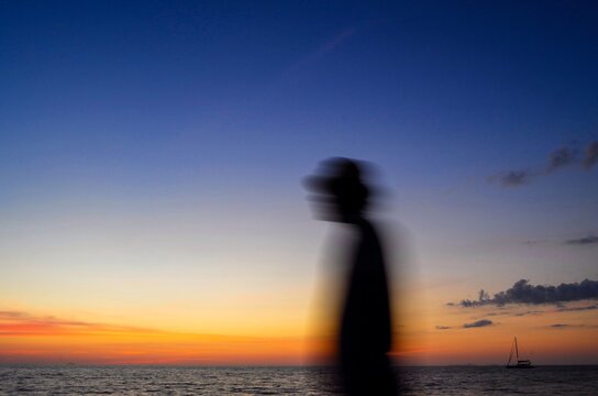 Motion blurred silhouette of man on the beach at sunset background.Abstract picture.