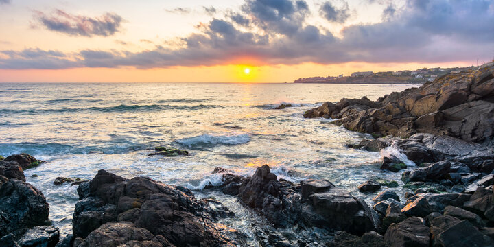 coast of the ocean at sunset. beautiful landscape with rocks in the water. gorgeous cloudscape above the sun and horizon. concept of calmness and mediatation