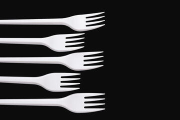 Five white plastic forks isolated on a black background.