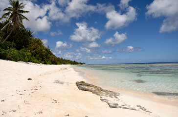 Tropical Western Pacific sandy and lava rock beach with coconut trees and clear blue waters in Guam, Micronesia