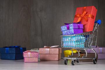 Shopping carts with gifts inside on a dark wood background.