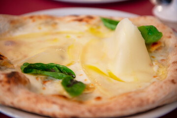 Delicious tasty traditional italian pizza Four Cheeses (Quattro formaggi) - set of cheeses, basil and crispy dough cooked in the oven in restaurant or pizzeria, detail, soft focus