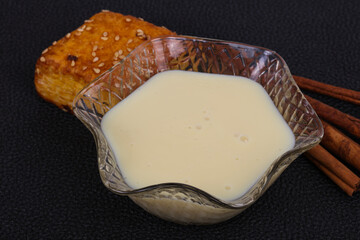 Condenced milk in the bowl with sinnamon and pastry