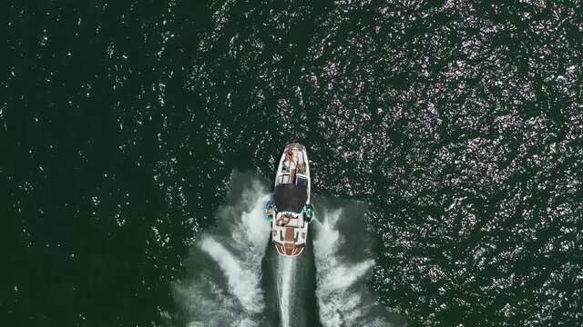 Speed boat with people roaring across the Sea at high speed, Aerial view.