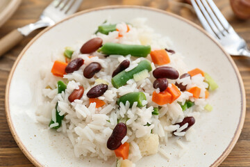Plate with tasty rice, beans and vegetables on table, closeup