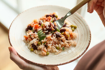 Woman eating tasty rice with beans and vegetables, closeup