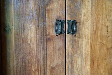 natural lacquered wooden doors, metallic black retro handles, horizontal photo, old background
